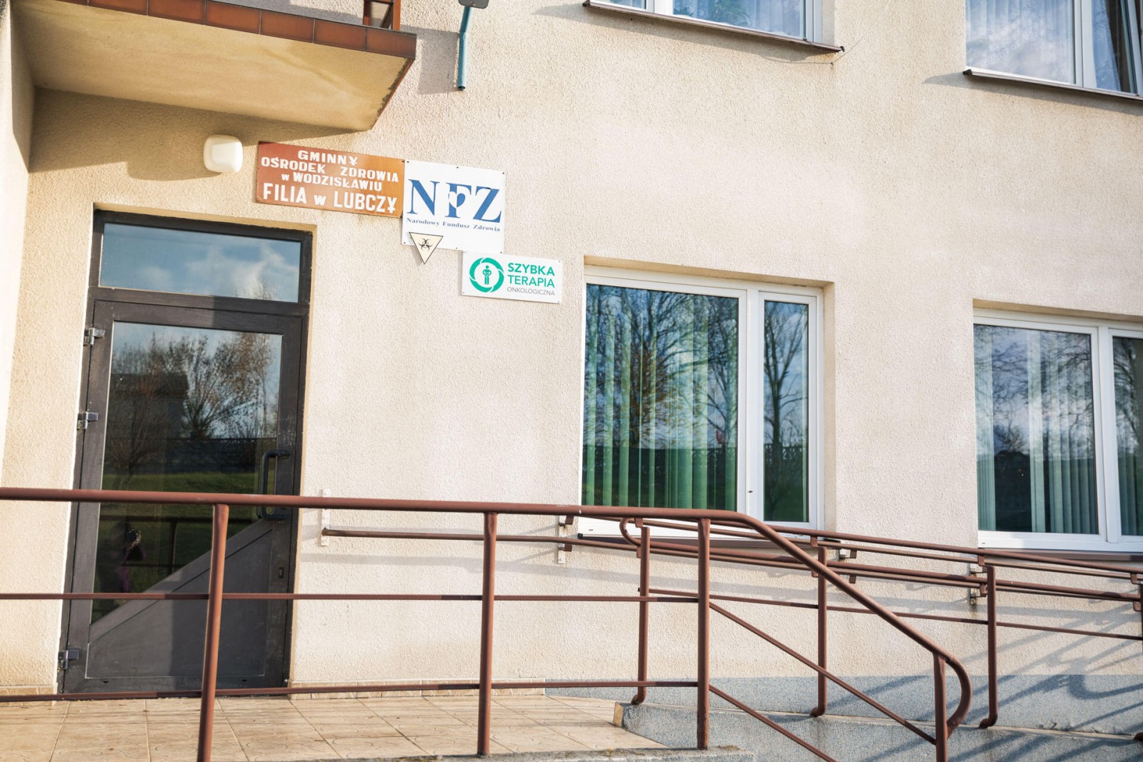 Wejście do budynku Gminnego Ośrodka Zdrowia w Wodzisławiu, filia w Lubczy– przed wejściem znajdują tablice informacyjne.
