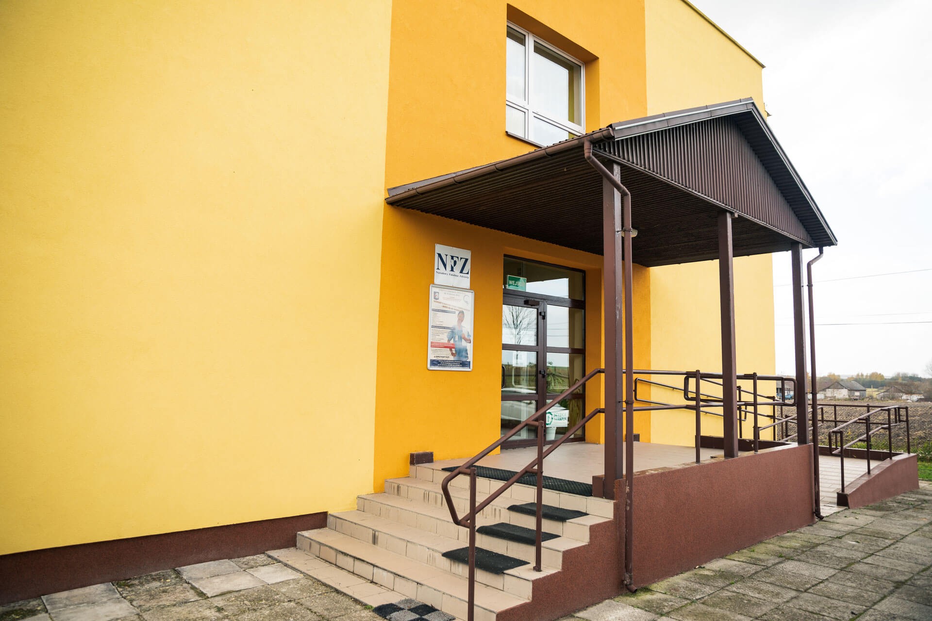 Wejście do budynku Gminnego Ośrodka Zdrowia w Wodzisławiu, filia w Niegosławicach – przed wejściem znajdują się schody.